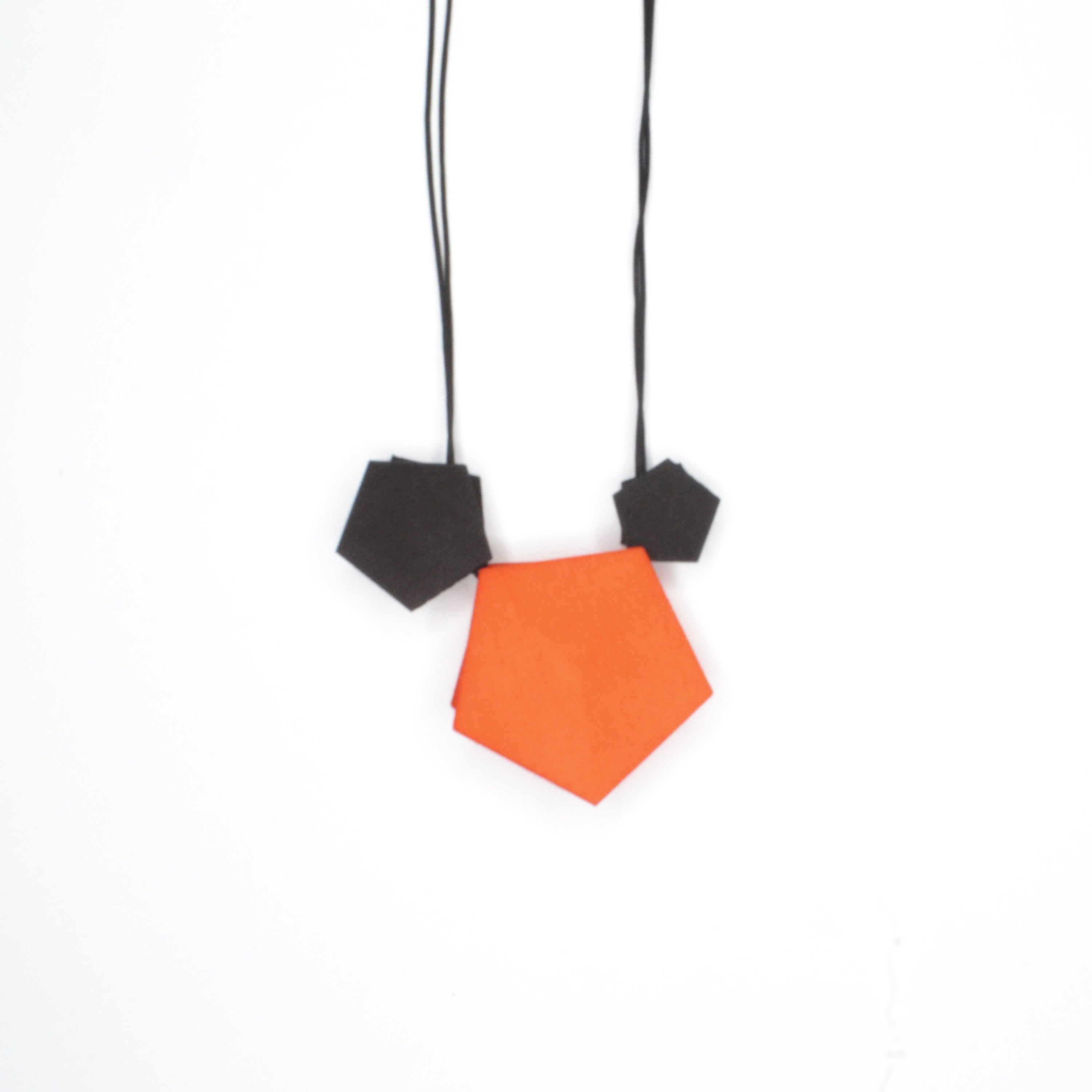 Vertigo 3 Element Necklace featuring three geometric pentagons on a black nylon cord, showcasing vibrant colors and a sterling silver bead for length adjustment.