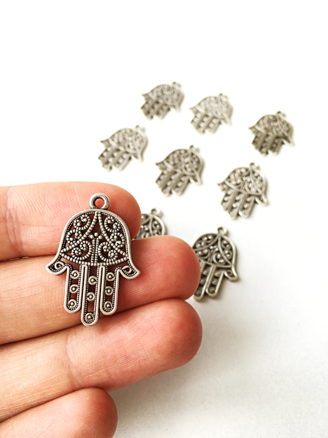 Three handmade silver plated hamsa charm connectors with an antique silver finish, ideal for DIY jewelry projects.