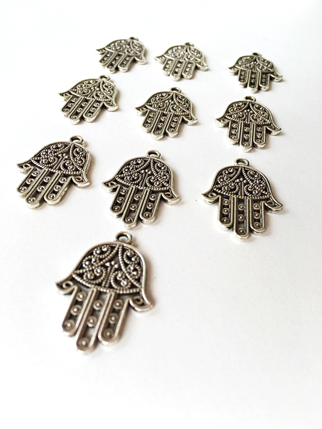 Three handmade silver plated hamsa charm connectors with an antique silver finish, ideal for DIY jewelry projects.