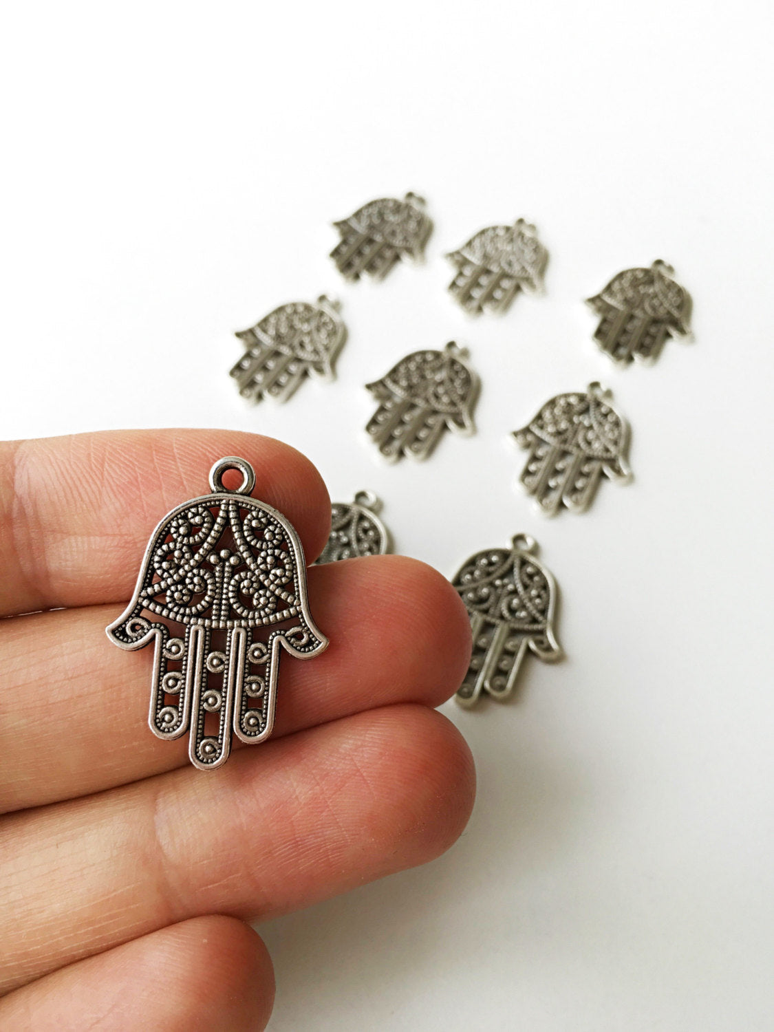 Three handmade silver plated hamsa charm connectors with an antique silver finish, ideal for DIY jewelry projects.