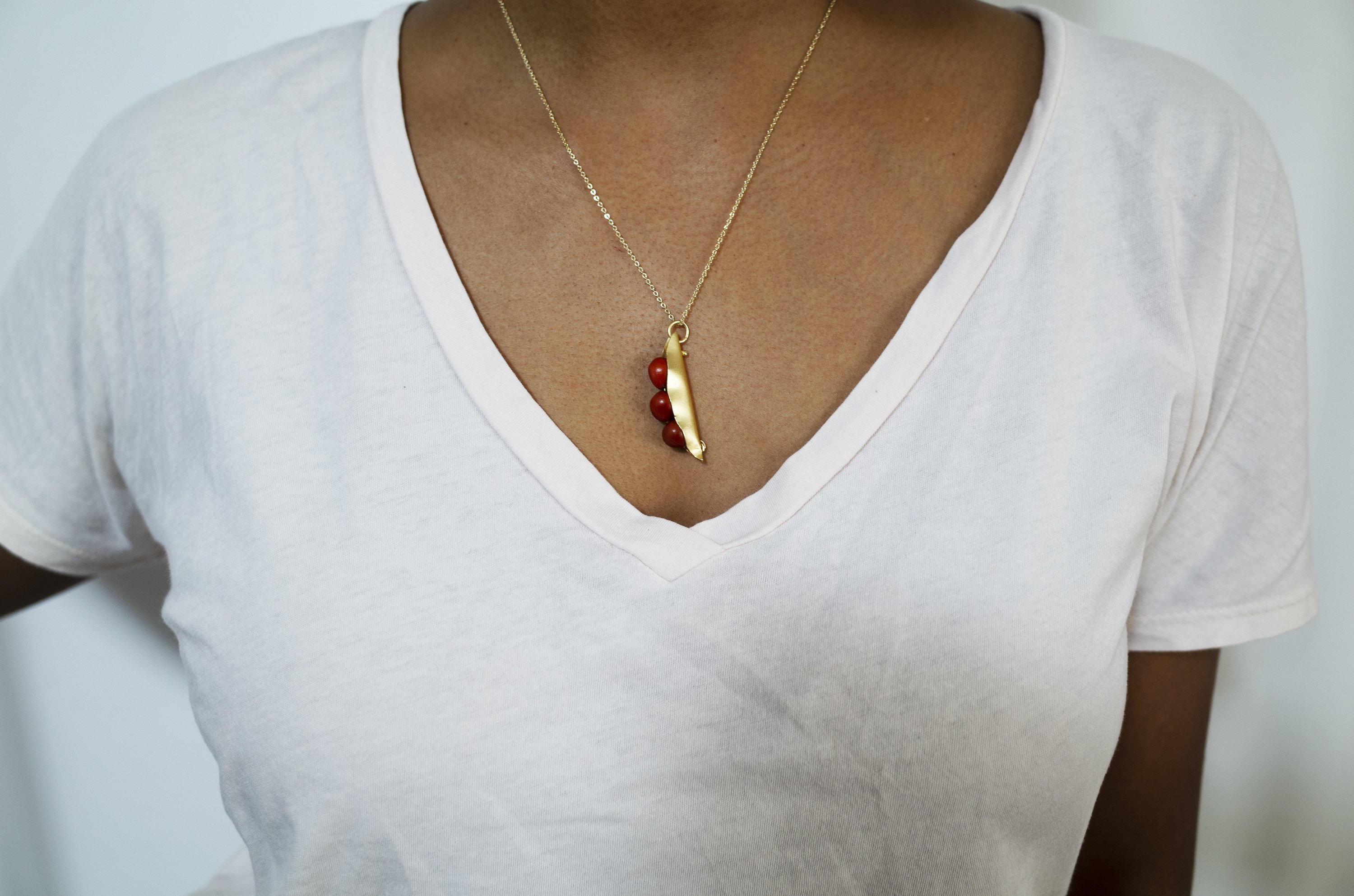 A handcrafted 3 Seeds in a Pod Pendant featuring natural Manjadi Kuru seeds on a gold plated chain, showcasing vibrant colors.