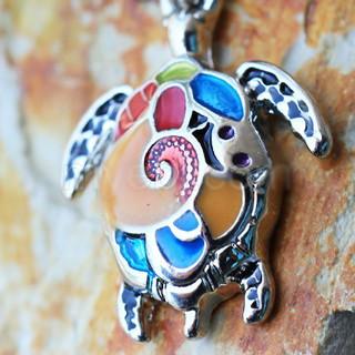 A colorful 316L stainless steel navel ring featuring a detailed sea turtle dangle with sparkling cubic zirconia accents.