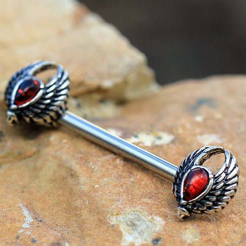 A beautifully crafted 316L stainless steel nipple bar featuring ornate wings with black accents and a dark red teardrop-shaped cubic zirconia.