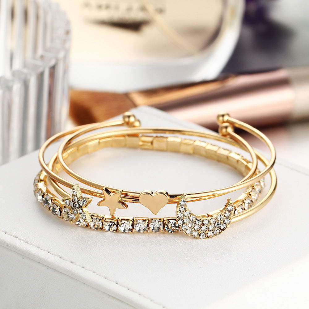 A luxurious 4 Piece Celestial Bangle Set featuring 18K gold plating and sparkling crystals, elegantly displayed on a soft surface.