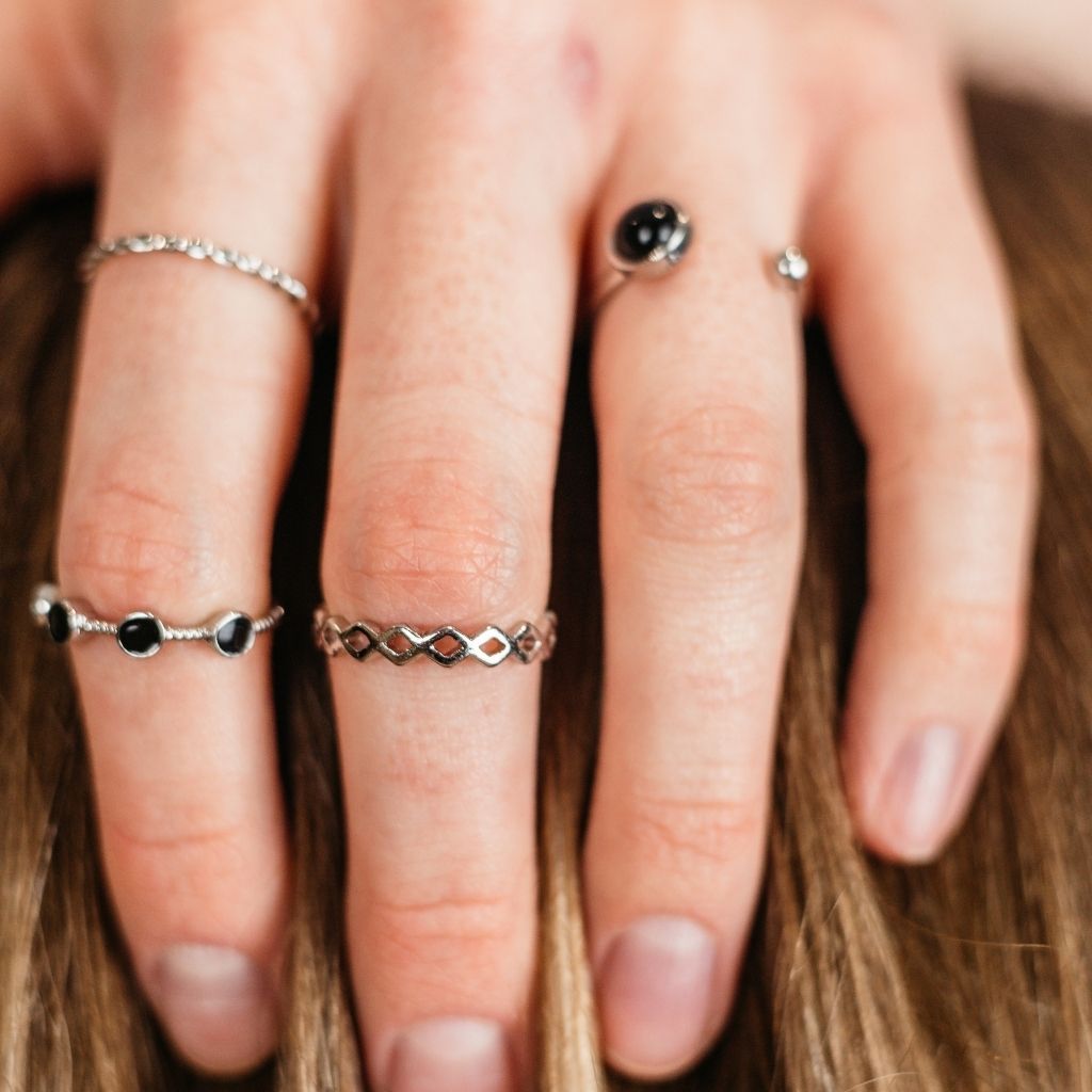 A stylish 4 piece silver and black stone stacking dainty open knuckle ring set, showcasing elegant designs with black gemstones.