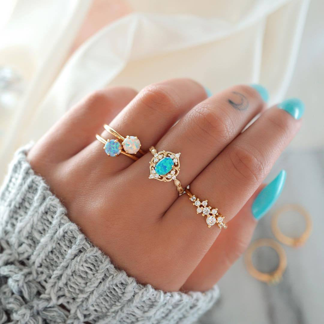 A beautiful 4-piece ring set featuring opal and white crystals, crafted from 14K gold-plated brass with a micro-pavé setting.