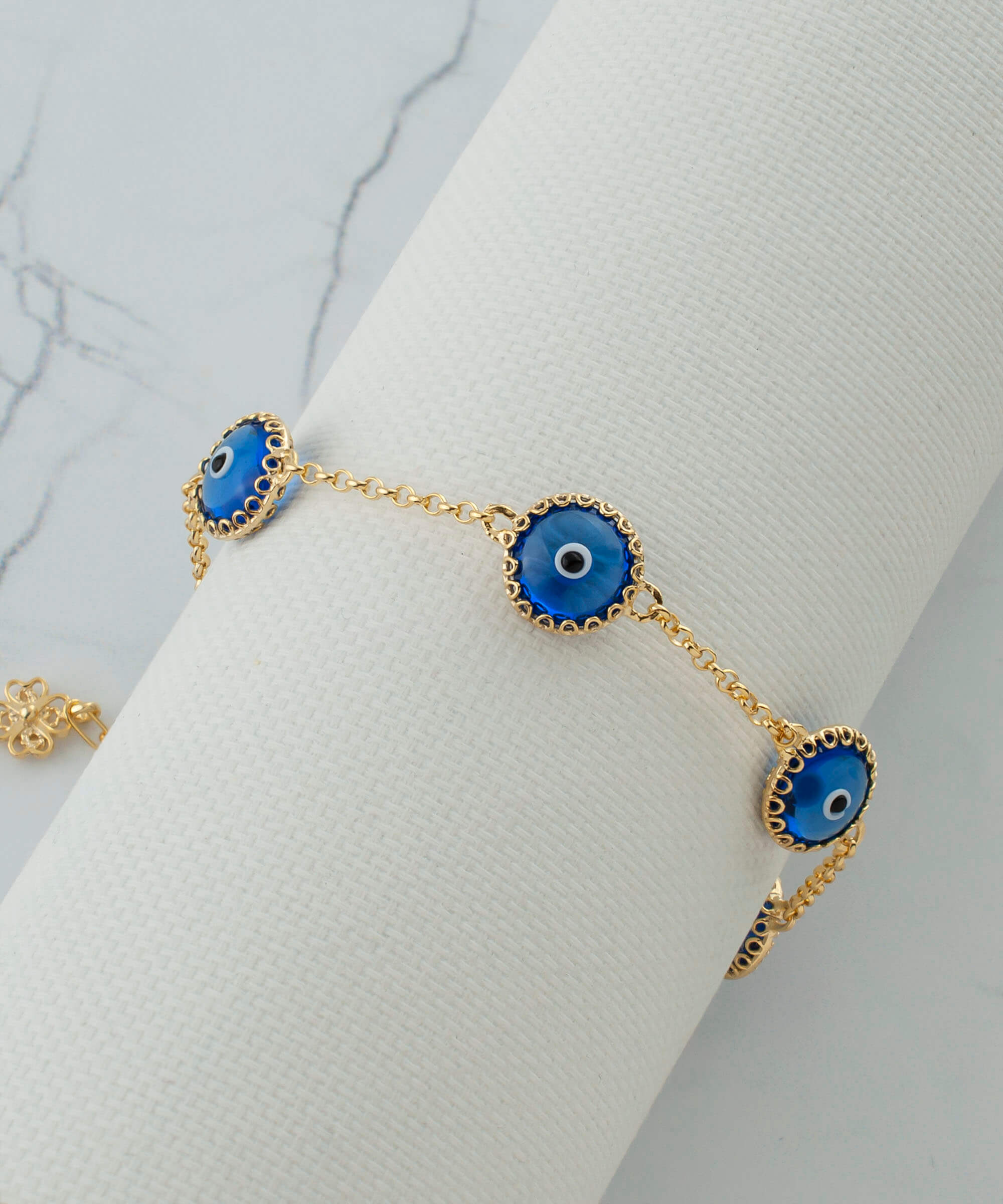 Gold plated sterling silver link bracelet featuring five blue evil eye beads, designed for women, with a lobster claw clasp.