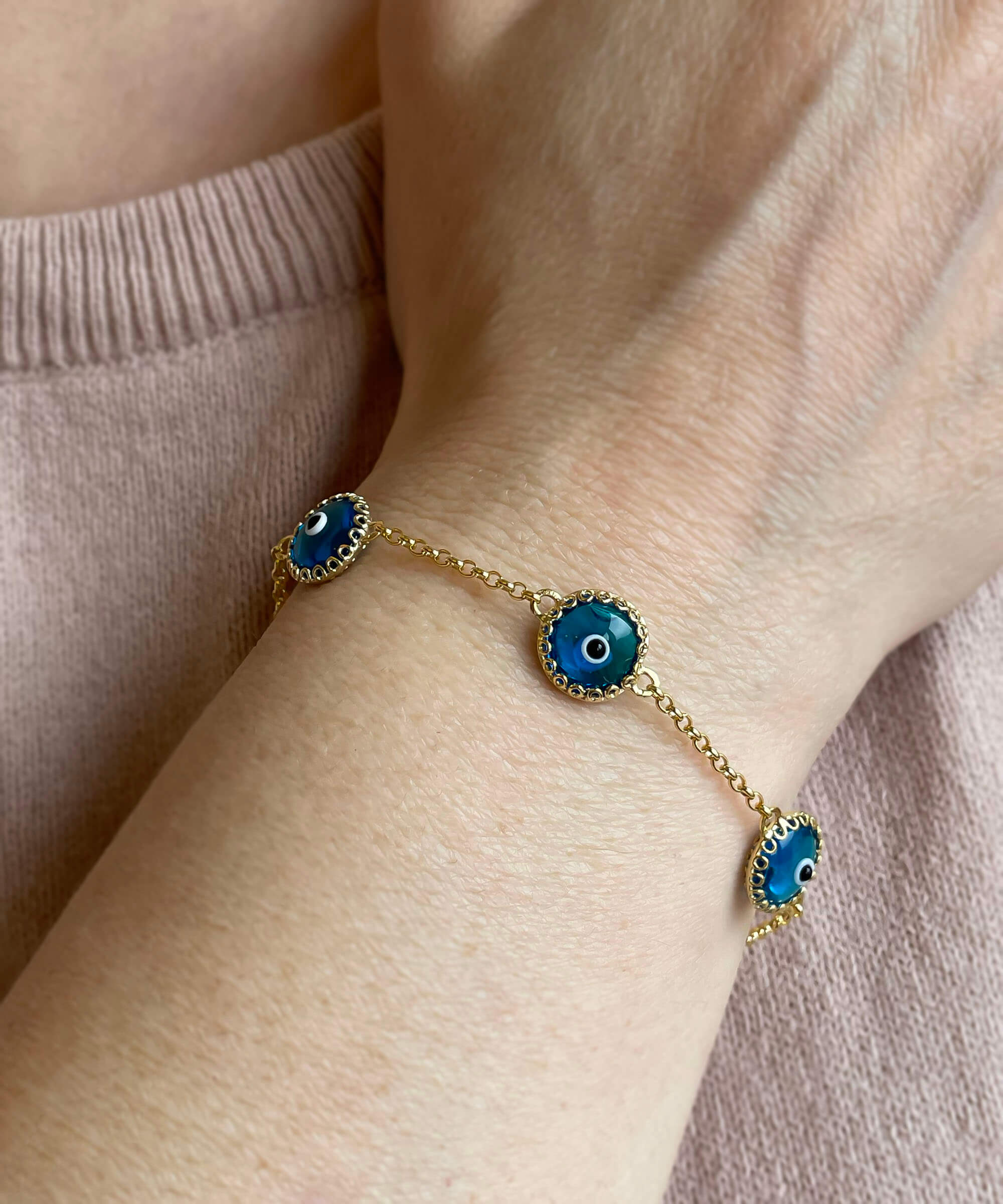 Gold plated sterling silver link bracelet featuring five blue evil eye beads, designed for women, with a lobster claw clasp.