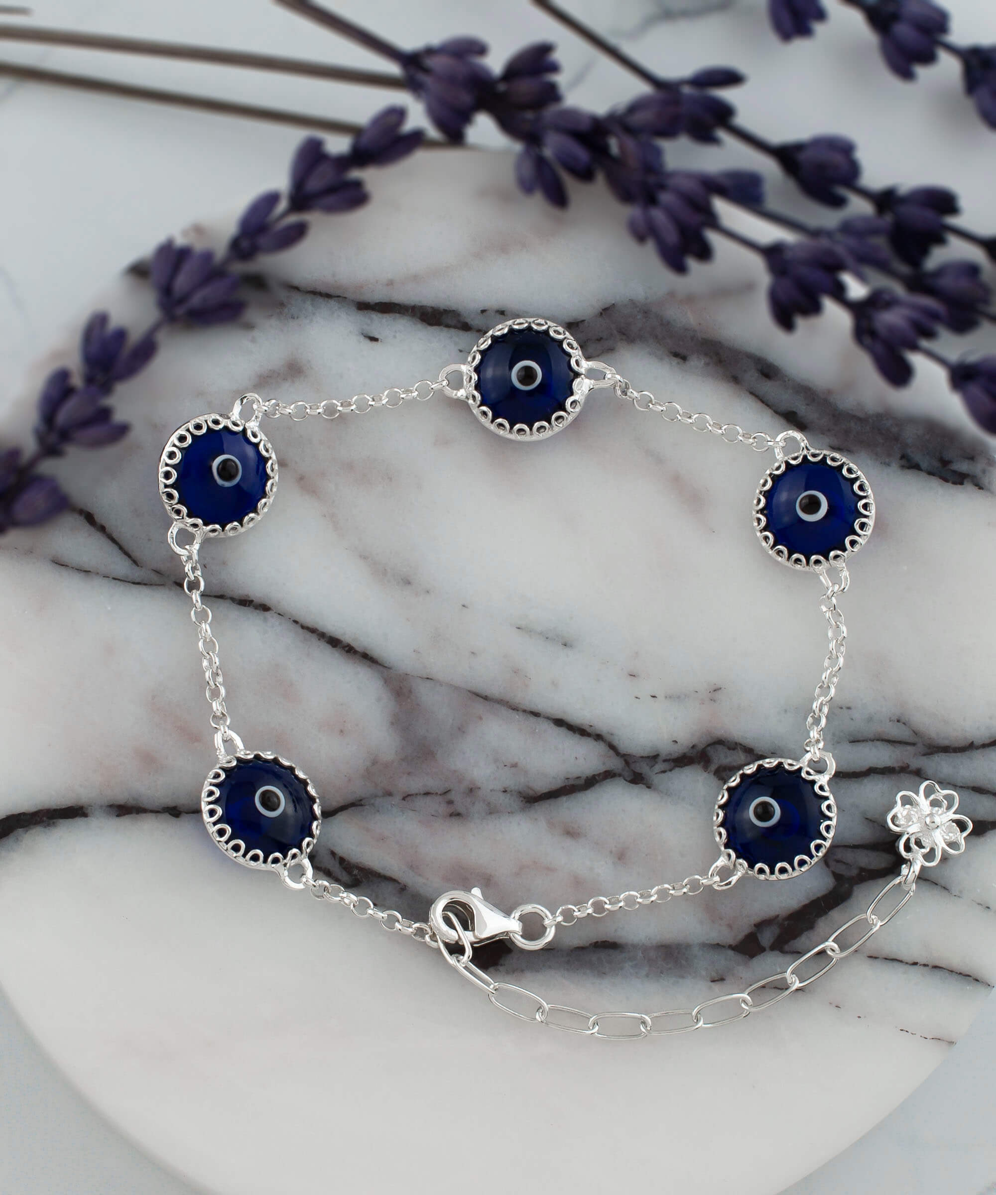 A stylish sterling silver link bracelet featuring five dark blue evil eye beads, designed for women, showcasing a secure lobster claw clasp.