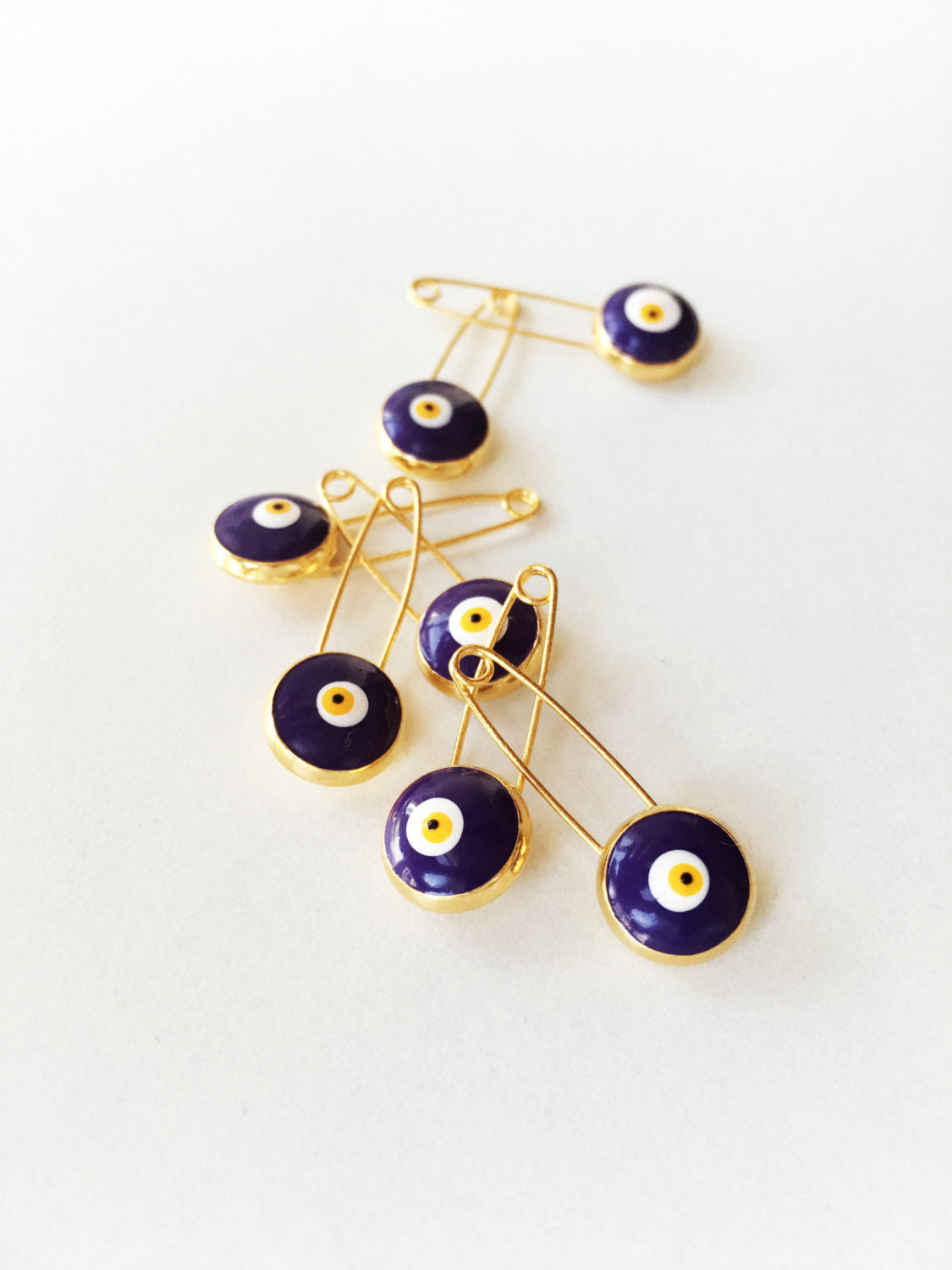 Set of 5 blue evil eye safety pins with gold plating, designed for baby protection and style.