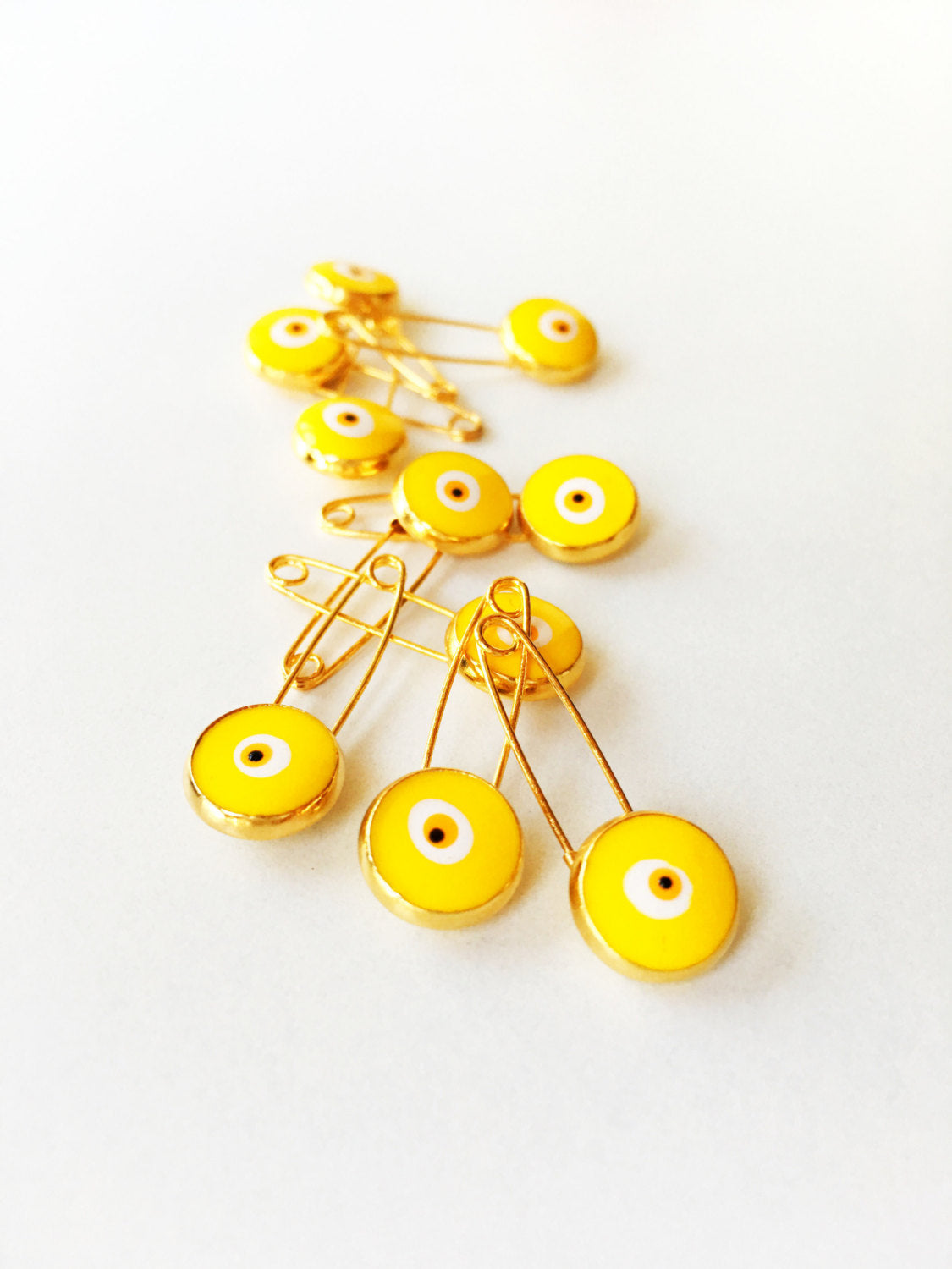 Set of 5 gold plated lucky evil eye safety pins with colorful enamel designs, perfect for baby protection.