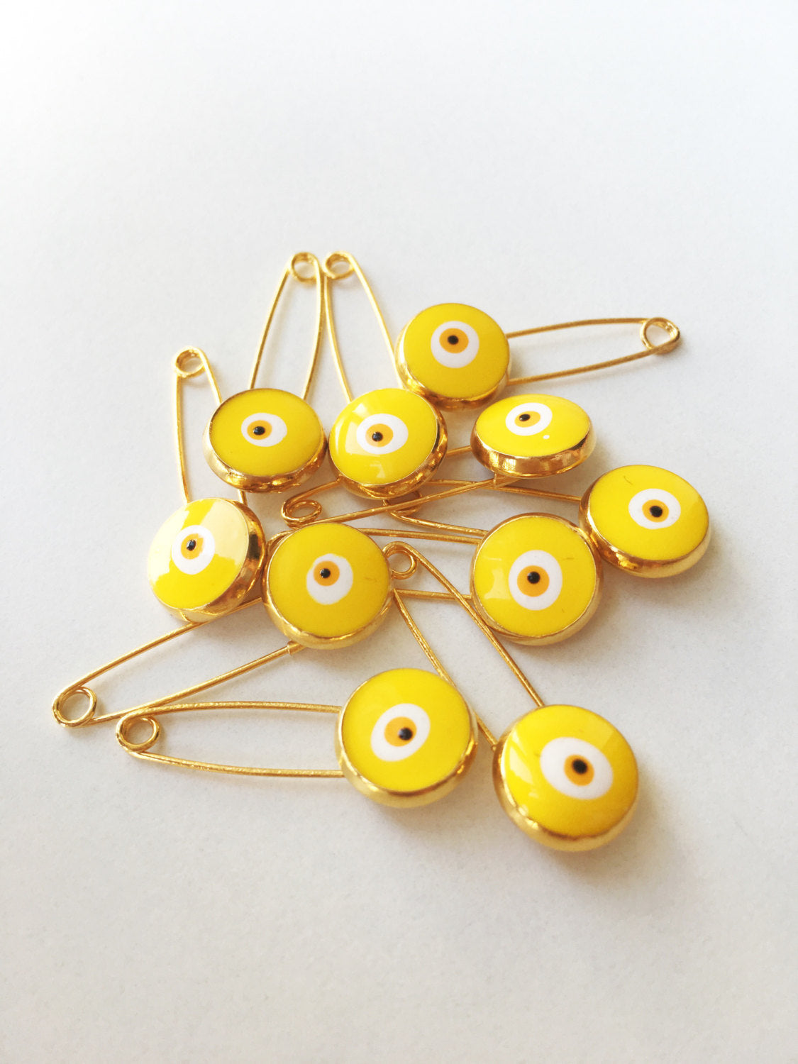 Set of 5 gold plated lucky evil eye safety pins with colorful enamel designs, perfect for baby protection.