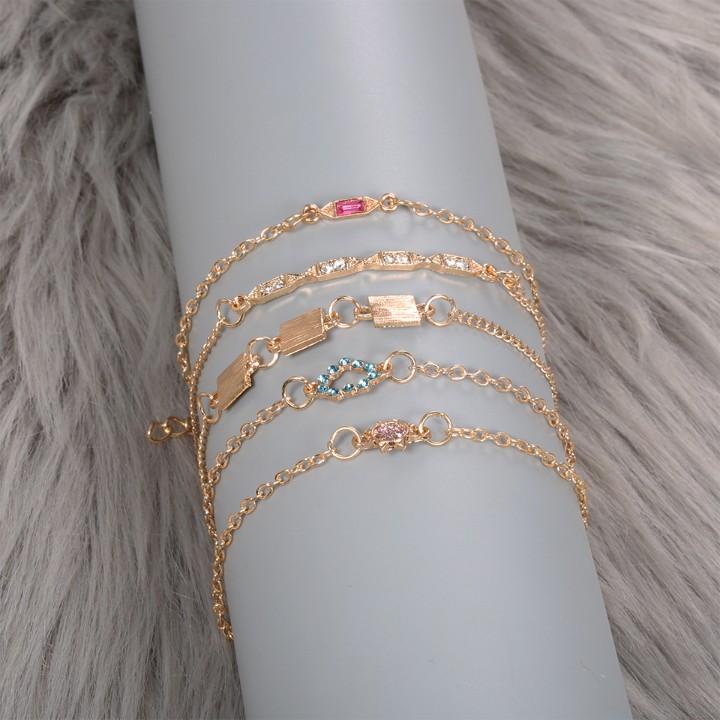 A stylish 5 piece bracelet set featuring cute and kitschy designs with colored crystals, elegantly plated in 14K gold.