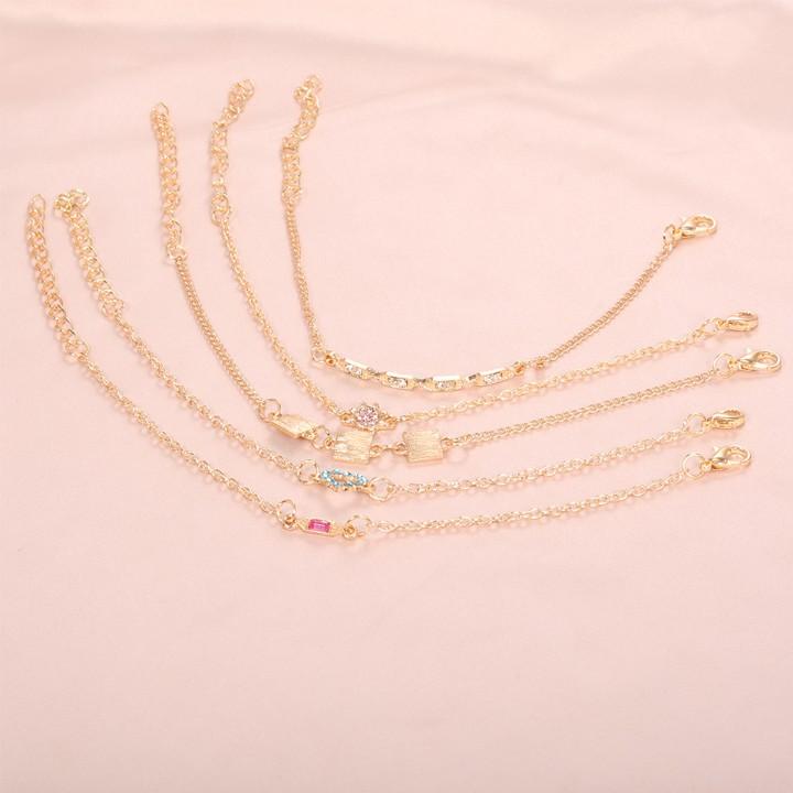 A stylish 5 piece bracelet set featuring cute and kitschy designs with colored crystals, elegantly plated in 14K gold.