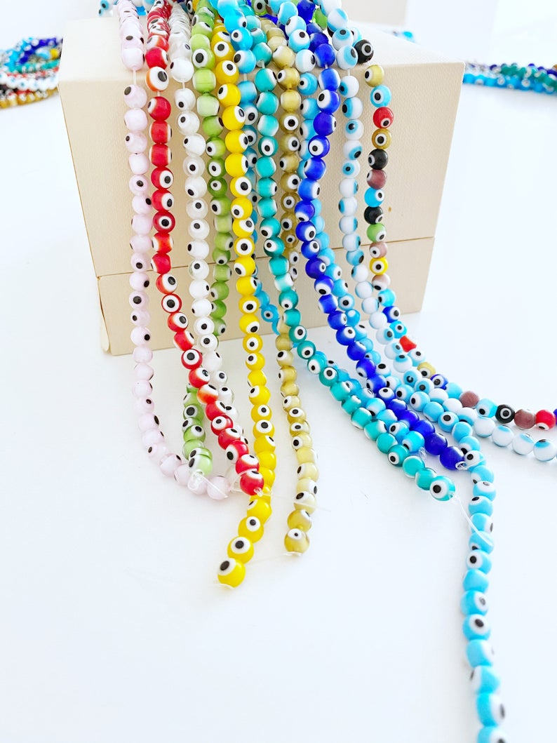 A collection of 50 pcs 8mm round glass evil eye beads in various colors including red, turquoise, and dark blue, ideal for jewelry making.