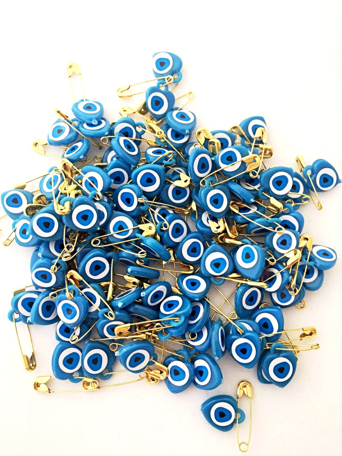 A collection of 100 pcs evil eye safety pins in various colors, featuring heart-shaped resin designs with evil eye beads.