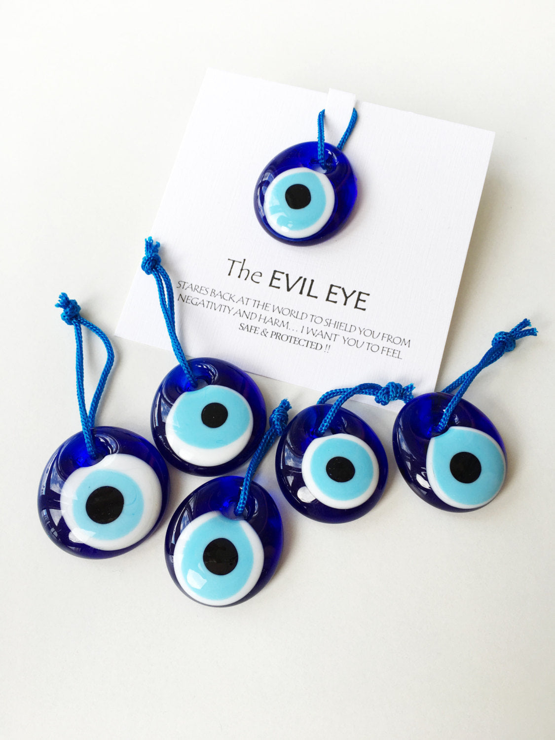 Five unique evil eye wedding favors with beads and personalized cards, symbolizing protection and good luck.