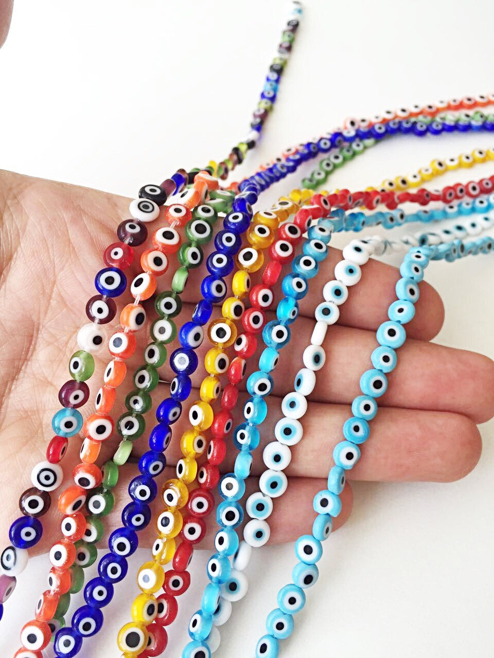 A strand of 6mm Turkish evil eye beads in various colors including red, yellow, green, and blue, showcasing their vibrant designs.