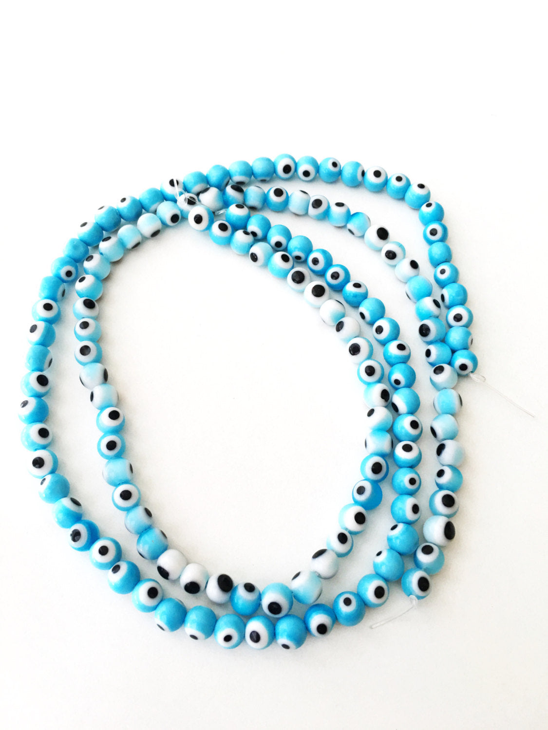 A strand of 6mm flat round baby blue glass evil eye beads, showcasing their unique handmade design.