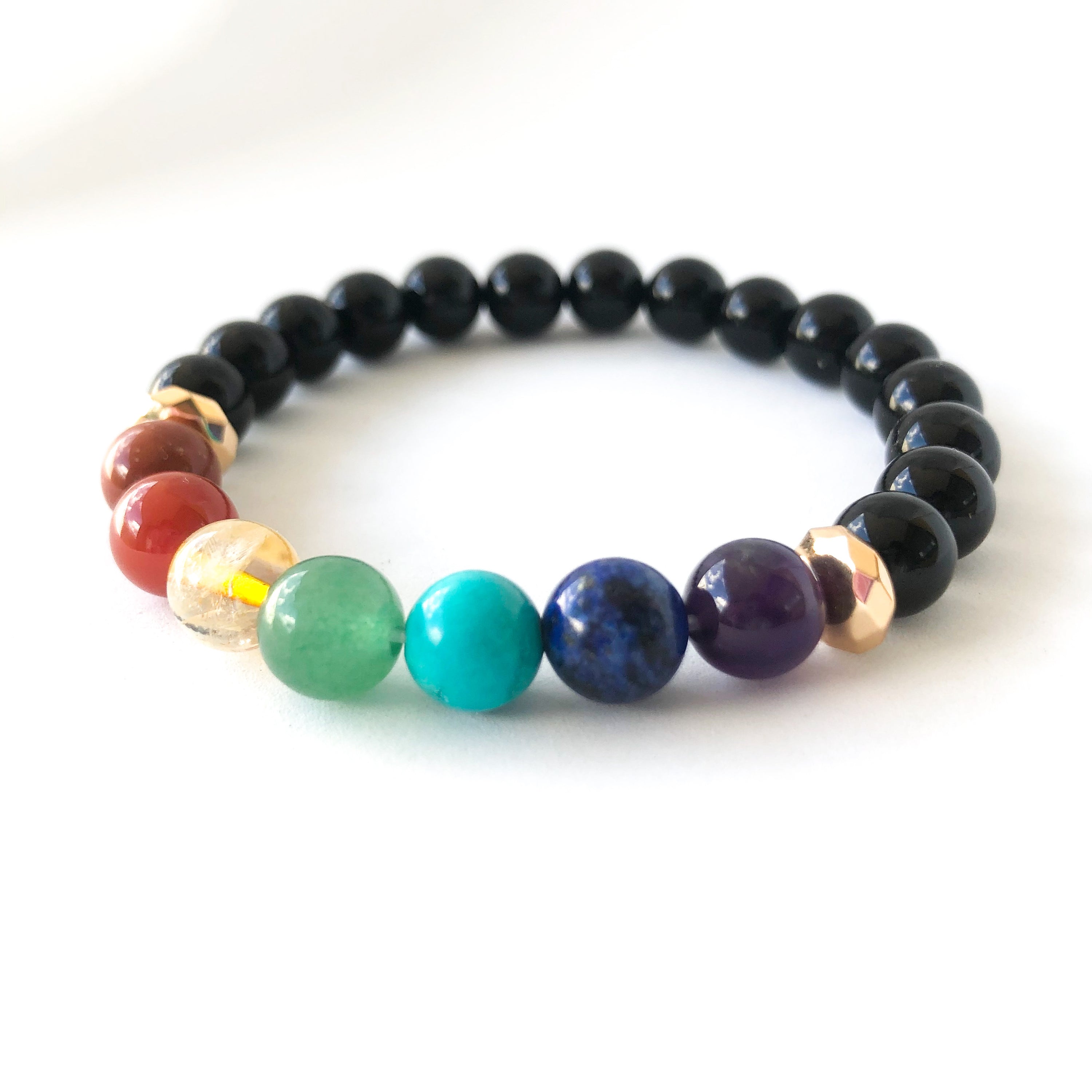 A colorful 7 Chakras Healing Bracelet featuring natural stones for each chakra, elegantly displayed on a soft surface.