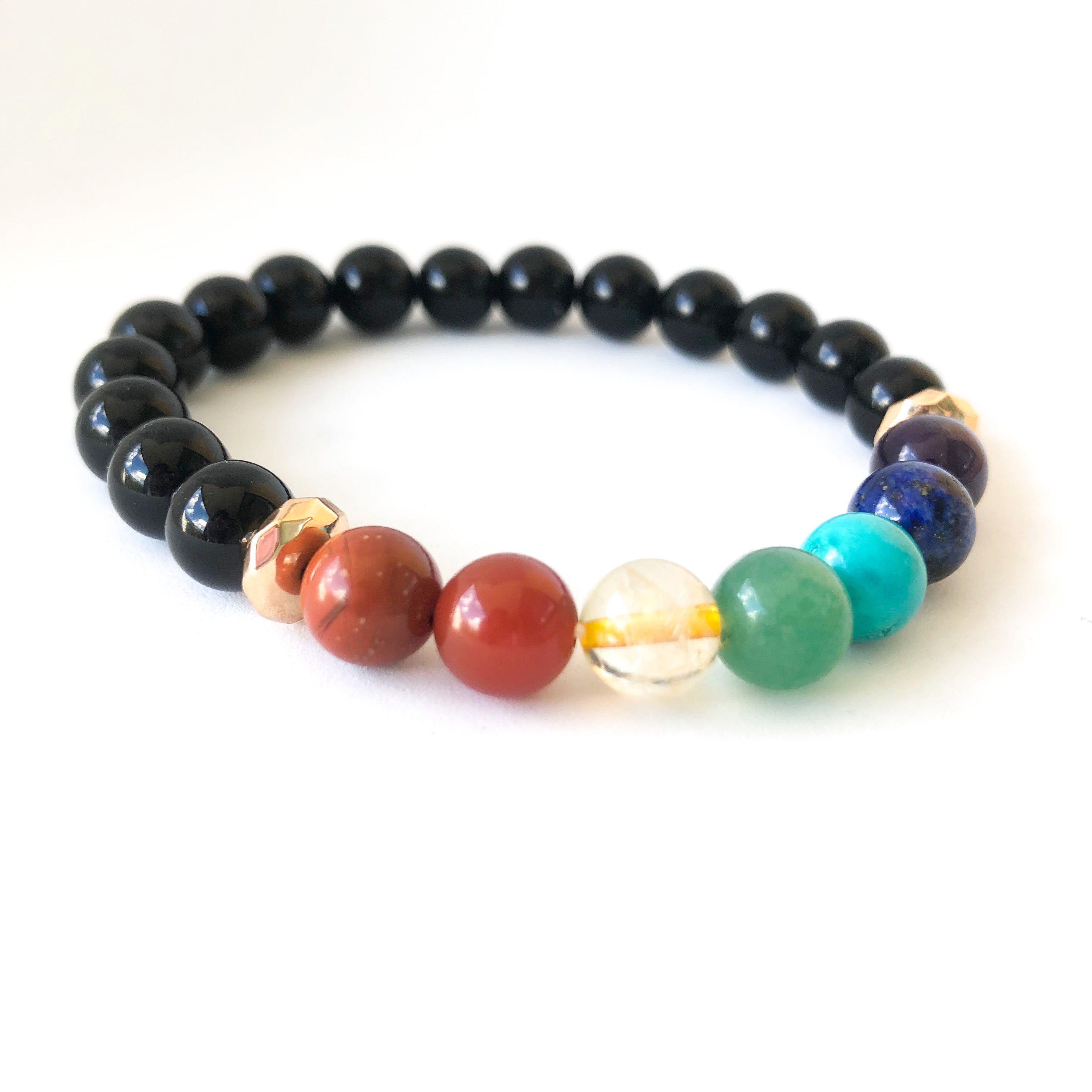 A colorful 7 Chakras Healing Bracelet featuring natural stones for each chakra, elegantly displayed on a soft surface.