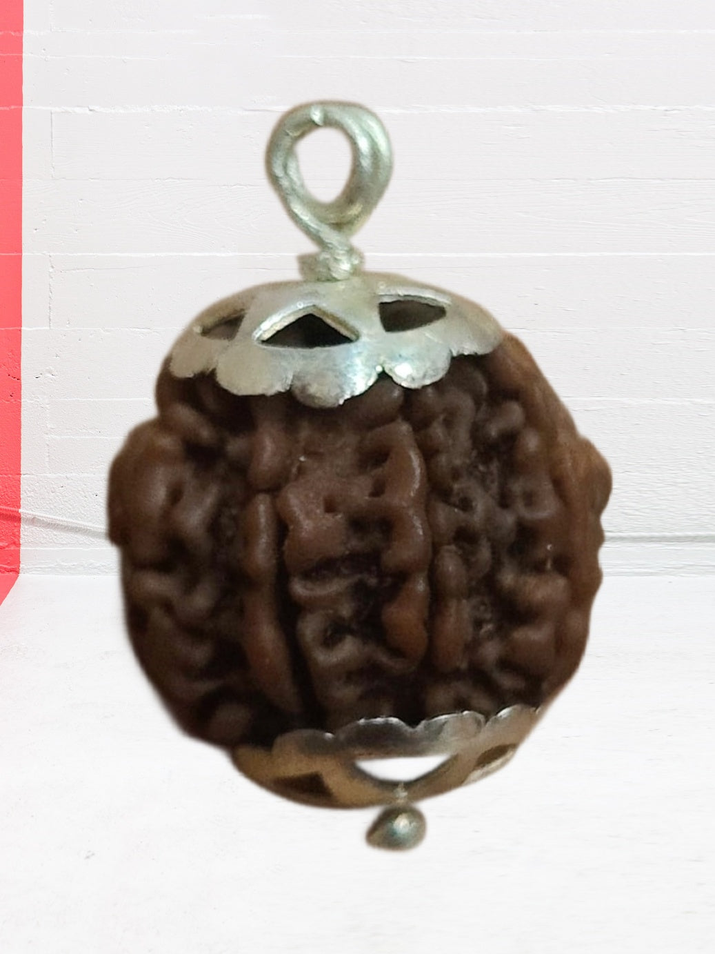 A 7 Face Rudraksha Pendant featuring a genuine 7 Mukhi bead with elegant silver capping, showcasing its brown oval shape.