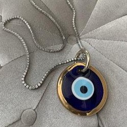 A 7cm handmade gold glass evil eye bead featuring a blue center and gold trim, symbolizing protection and good luck.