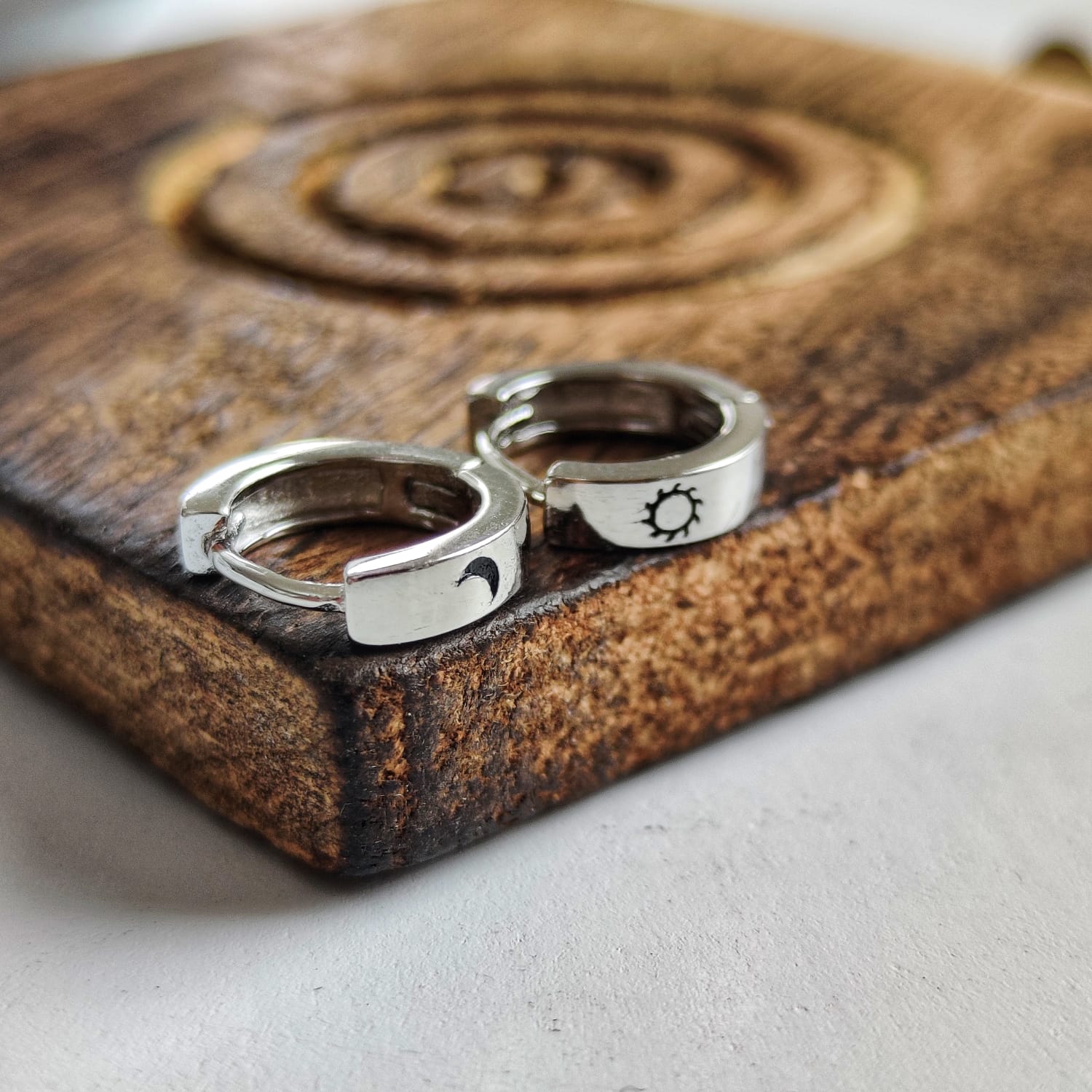 A pair of 925 silver slim hoop earrings featuring a minimalist sun and moon design, perfect for unisex wear.