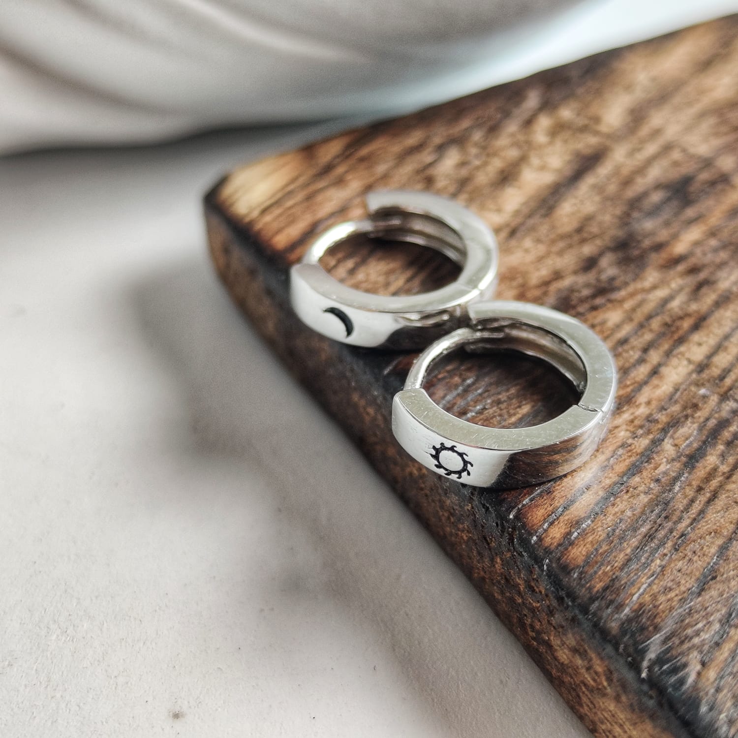 A pair of 925 silver slim hoop earrings featuring a minimalist sun and moon design, perfect for unisex wear.