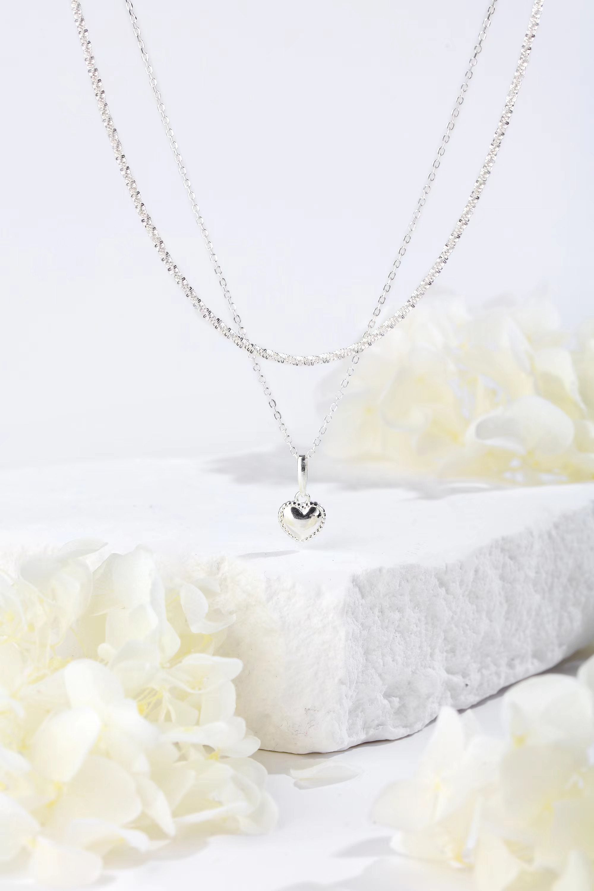 A delicate 925 sterling silver carved heart pendant necklace on a sleek chain, showcasing its elegant design.