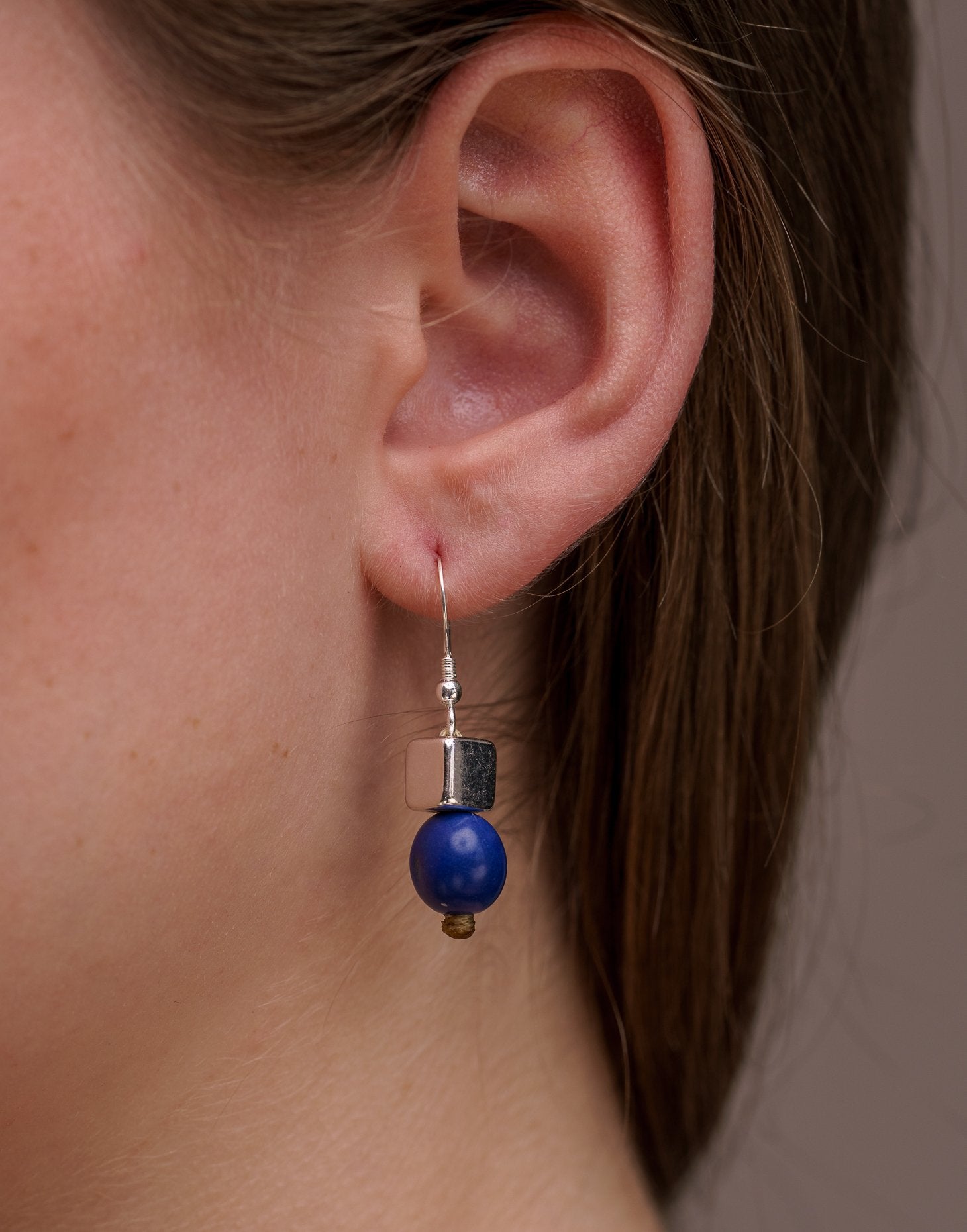 A pair of vibrant Acai Berry Earrings featuring pearl-sized acai seeds and silver accents, elegantly displayed in an eco-friendly bag.