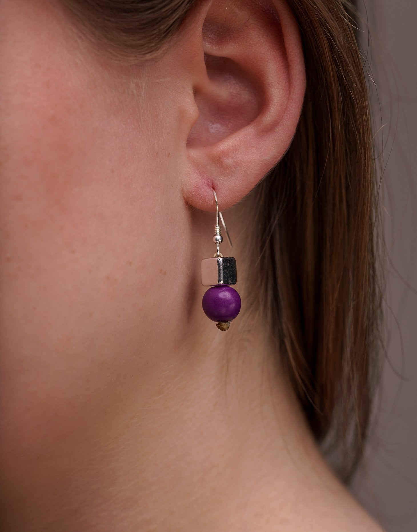 A pair of vibrant Acai Berry Earrings featuring pearl-sized acai seeds and silver accents, elegantly displayed in an eco-friendly bag.