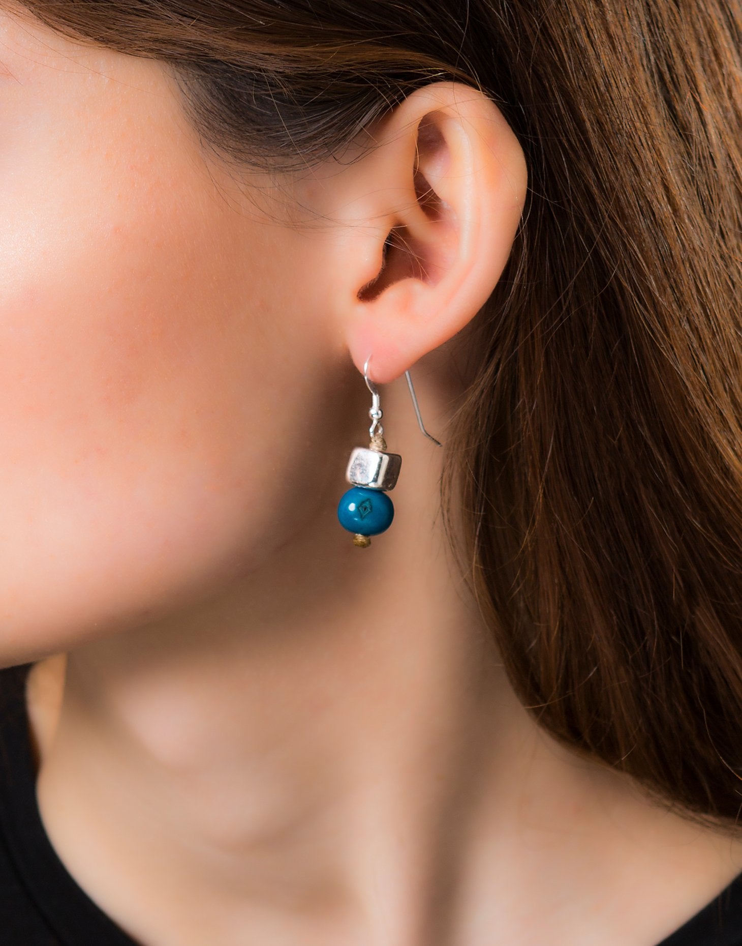 A pair of vibrant Acai Berry Earrings featuring pearl-sized acai seeds and silver accents, elegantly displayed in an eco-friendly bag.