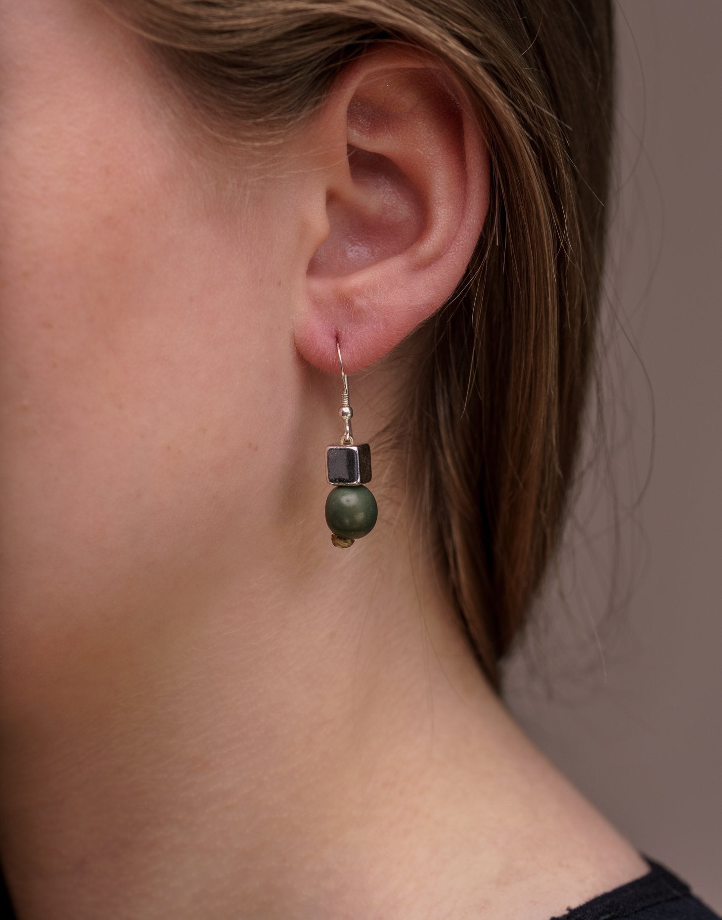 A pair of vibrant Acai Berry Earrings featuring pearl-sized acai seeds and silver accents, elegantly displayed in an eco-friendly bag.