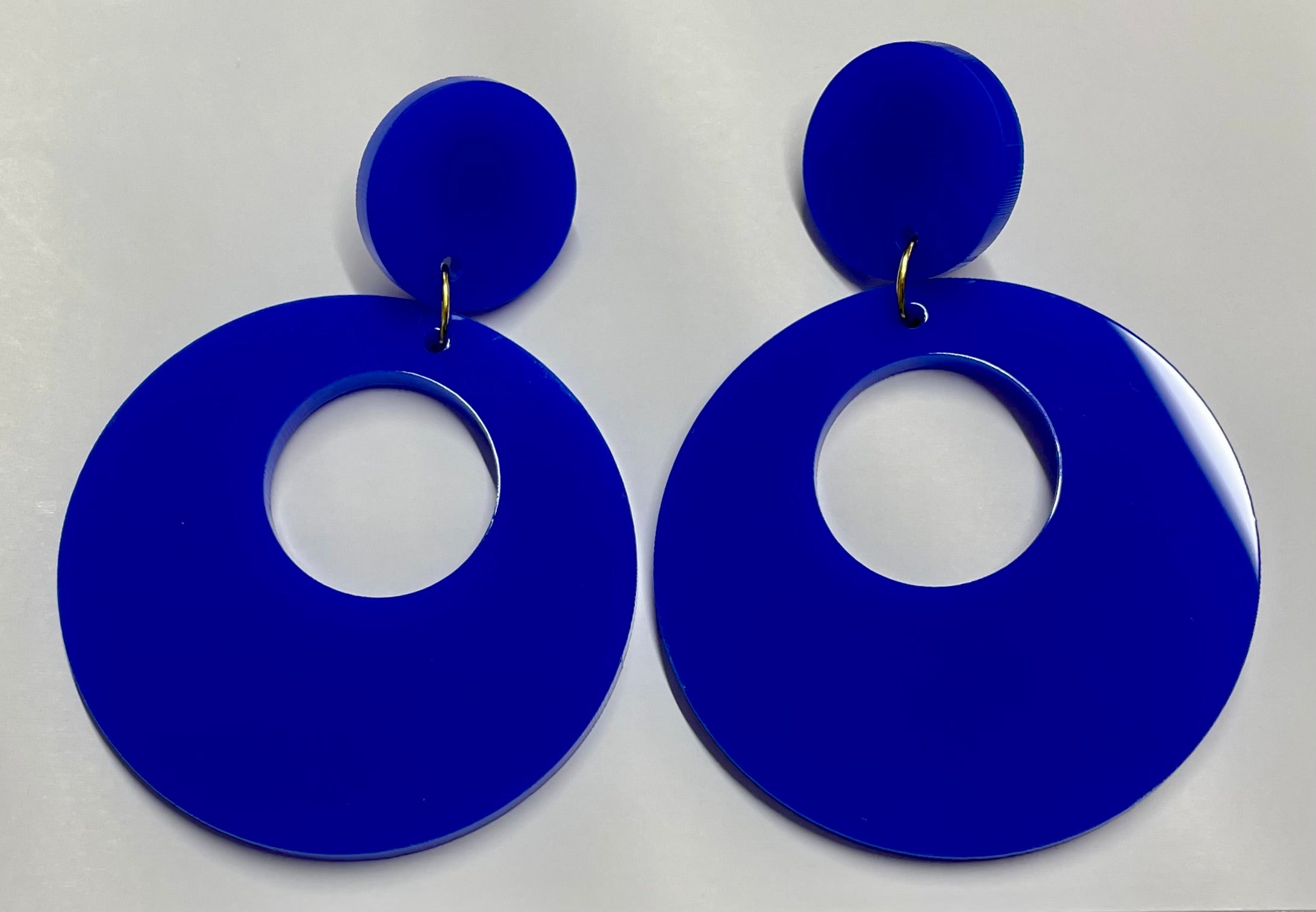 A pair of large acrylic hoop earrings in various colors, showcasing a stylish laser-cut design.