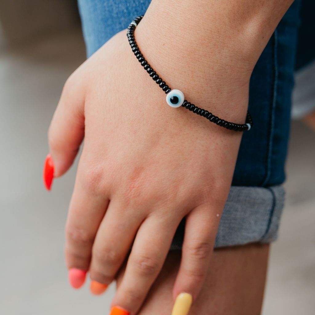 Adjustable black beads bracelet featuring an evil eye charm, combining boho and chic styles.