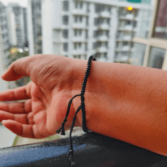 Adjustable black beads bracelet featuring an evil eye charm, combining boho and chic styles.