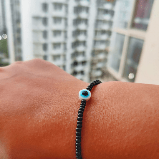 Adjustable black beads bracelet featuring an evil eye charm, combining boho and chic styles.