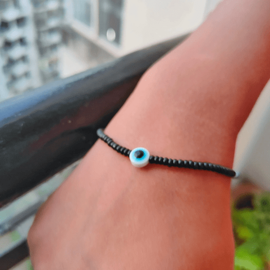 Adjustable black beads bracelet featuring an evil eye charm, combining boho and chic styles.