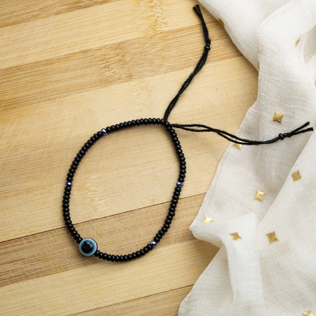 Adjustable black beads bracelet featuring an evil eye charm, combining boho and chic styles.