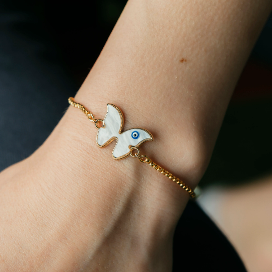 Adjustable Butterfly Evil Eye Bracelet featuring a white butterfly charm and blue evil eye on a gold chain, symbolizing protection and transformation.