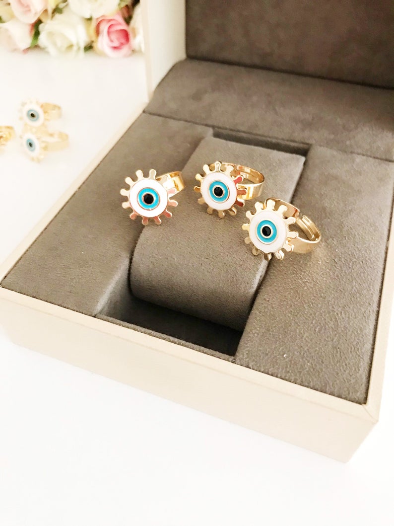 Adjustable Evil Eye Ring featuring a white charm and gold band, symbolizing protection and good luck.