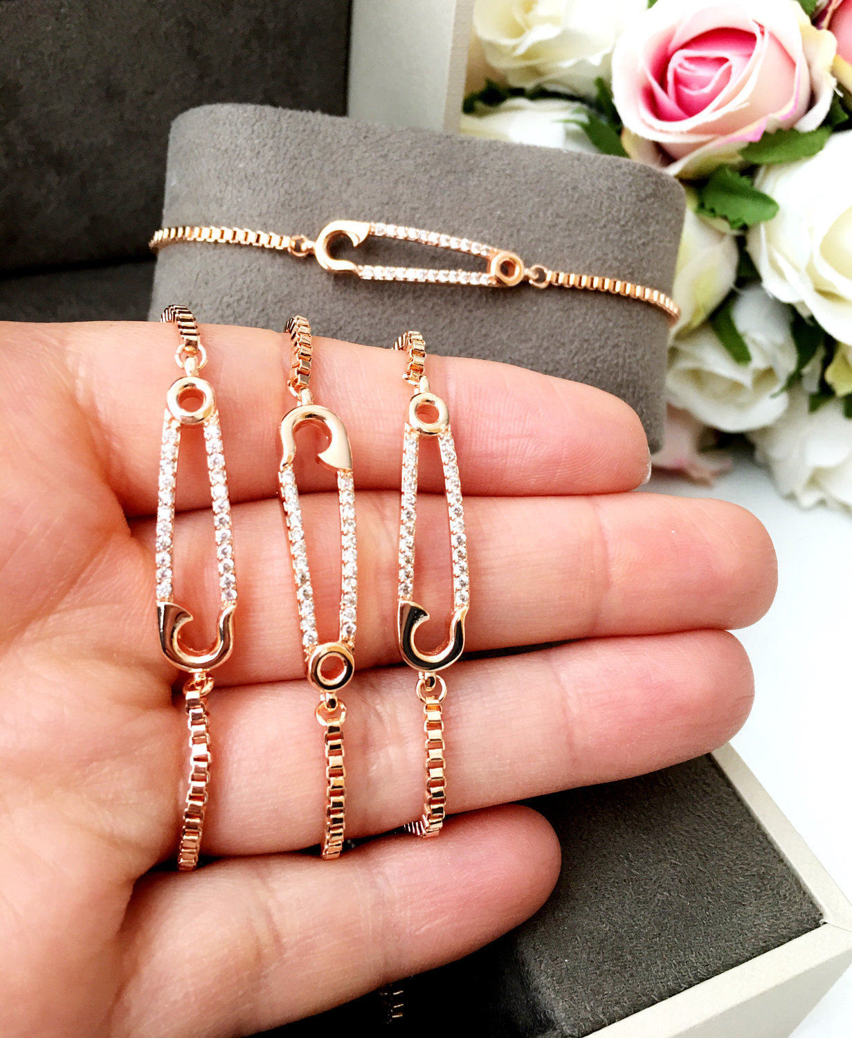 Adjustable rose gold safety pin bracelet featuring zirconia stones, showcasing a unique design and tarnish-resistant stainless steel.