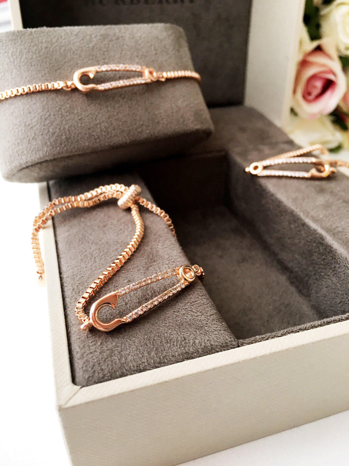 Adjustable rose gold safety pin bracelet featuring zirconia stones, showcasing a unique design and tarnish-resistant stainless steel.