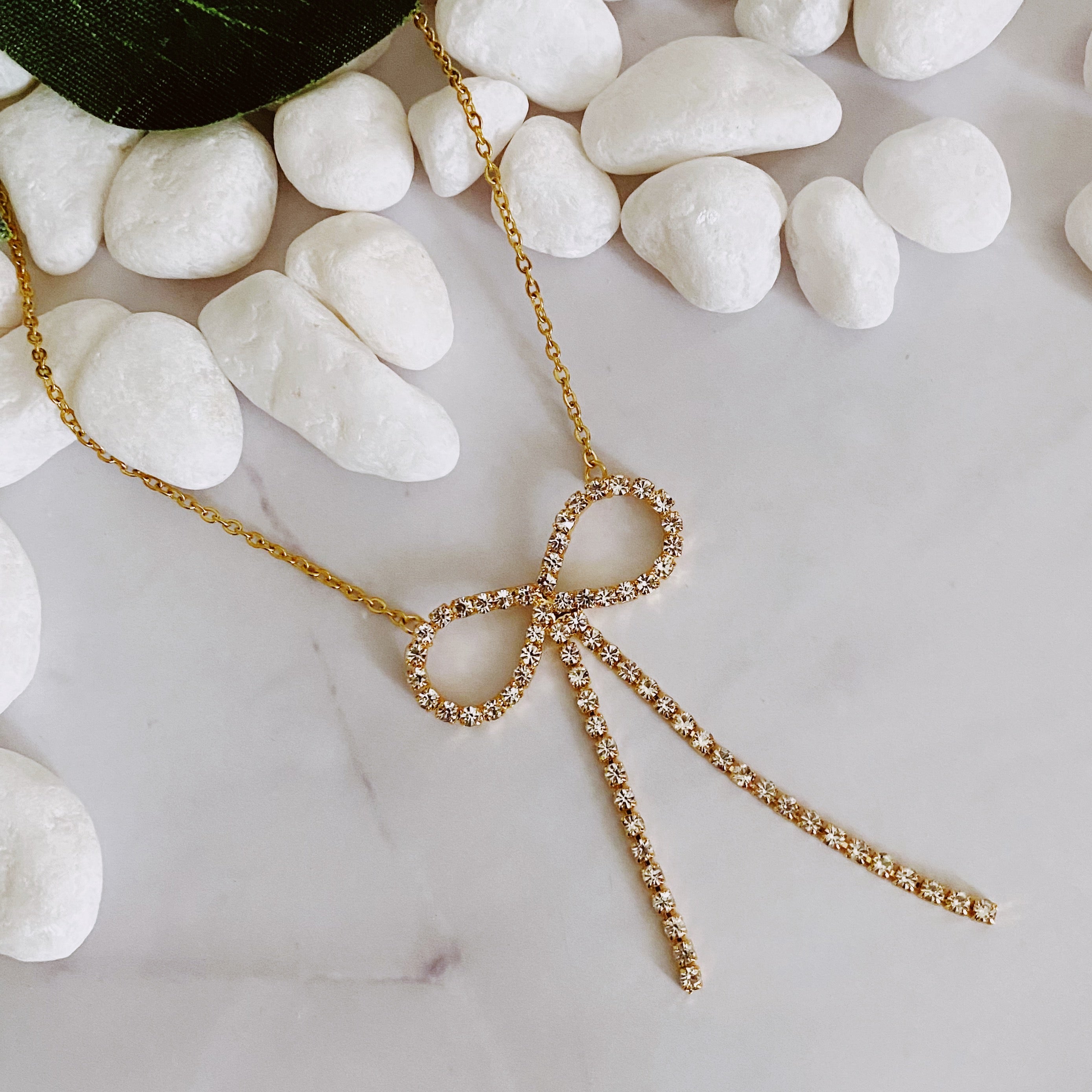 Adorable Shine Bow Necklace featuring a gold plated bow design with cubic zirconia accents, elegantly displayed on a soft background.