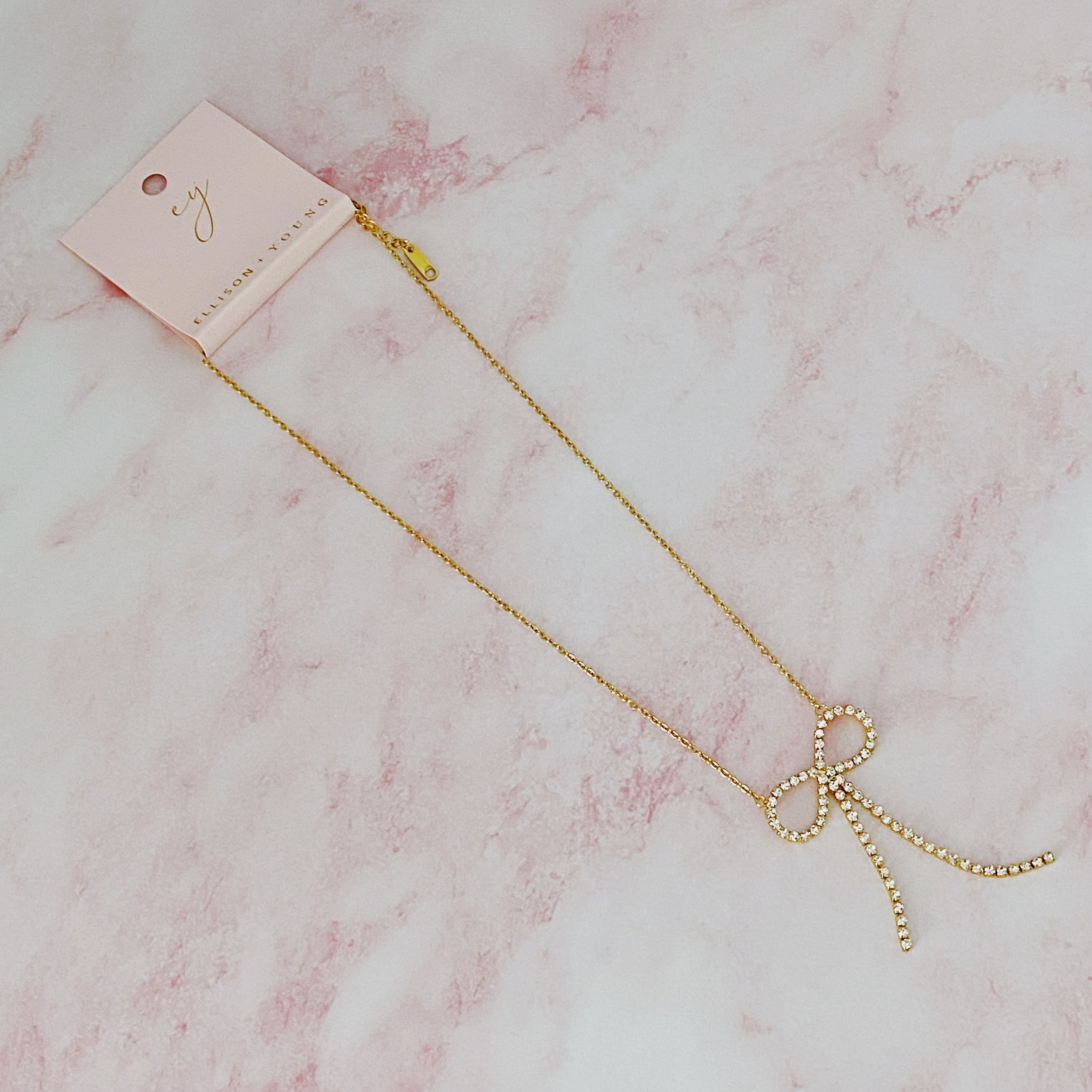 Adorable Shine Bow Necklace featuring a gold plated bow design with cubic zirconia accents, elegantly displayed on a soft background.