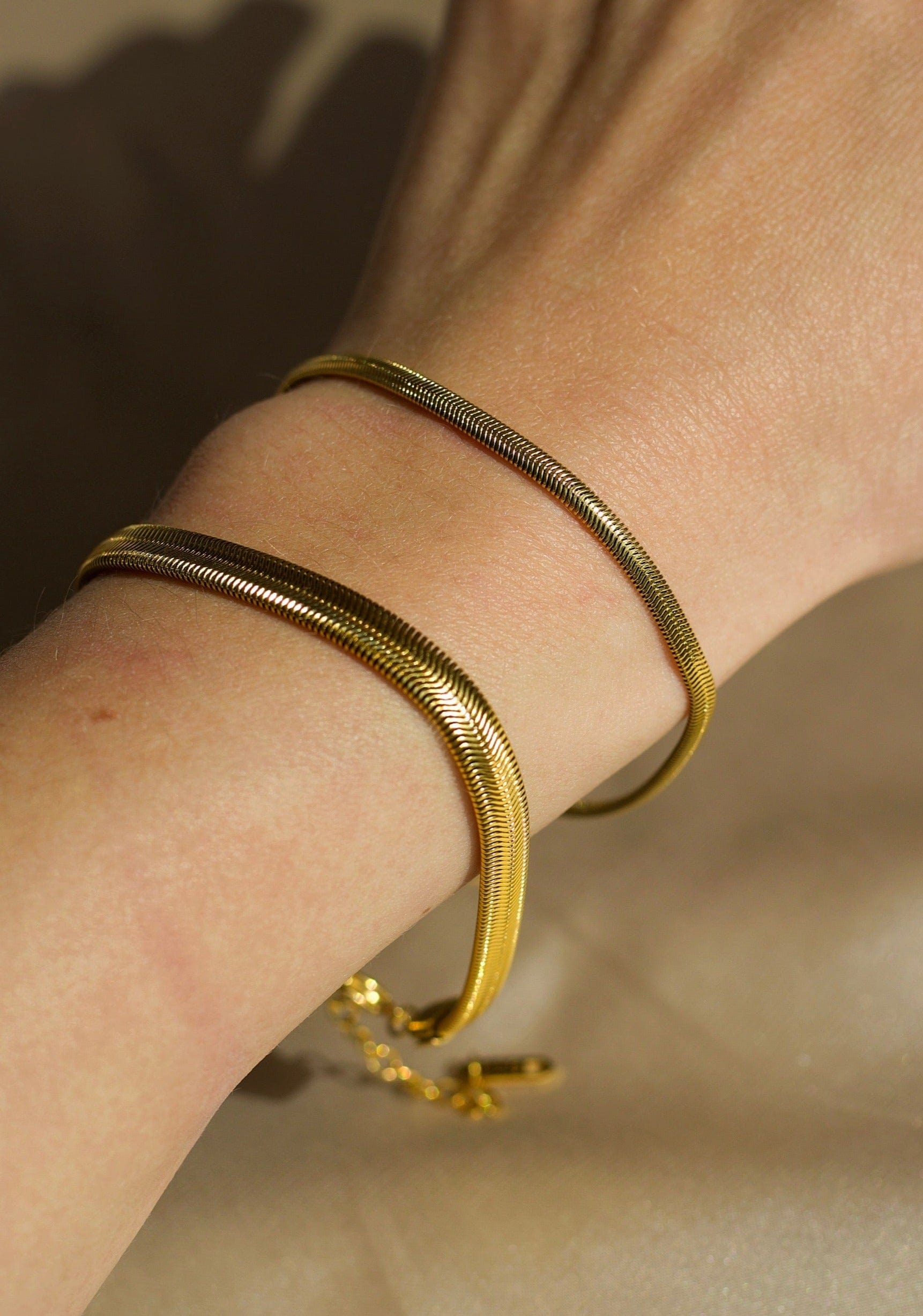 Alonna 3mm Women's Herringbone Bracelet in rich gold, showcasing its delicate design and adjustable clasp.