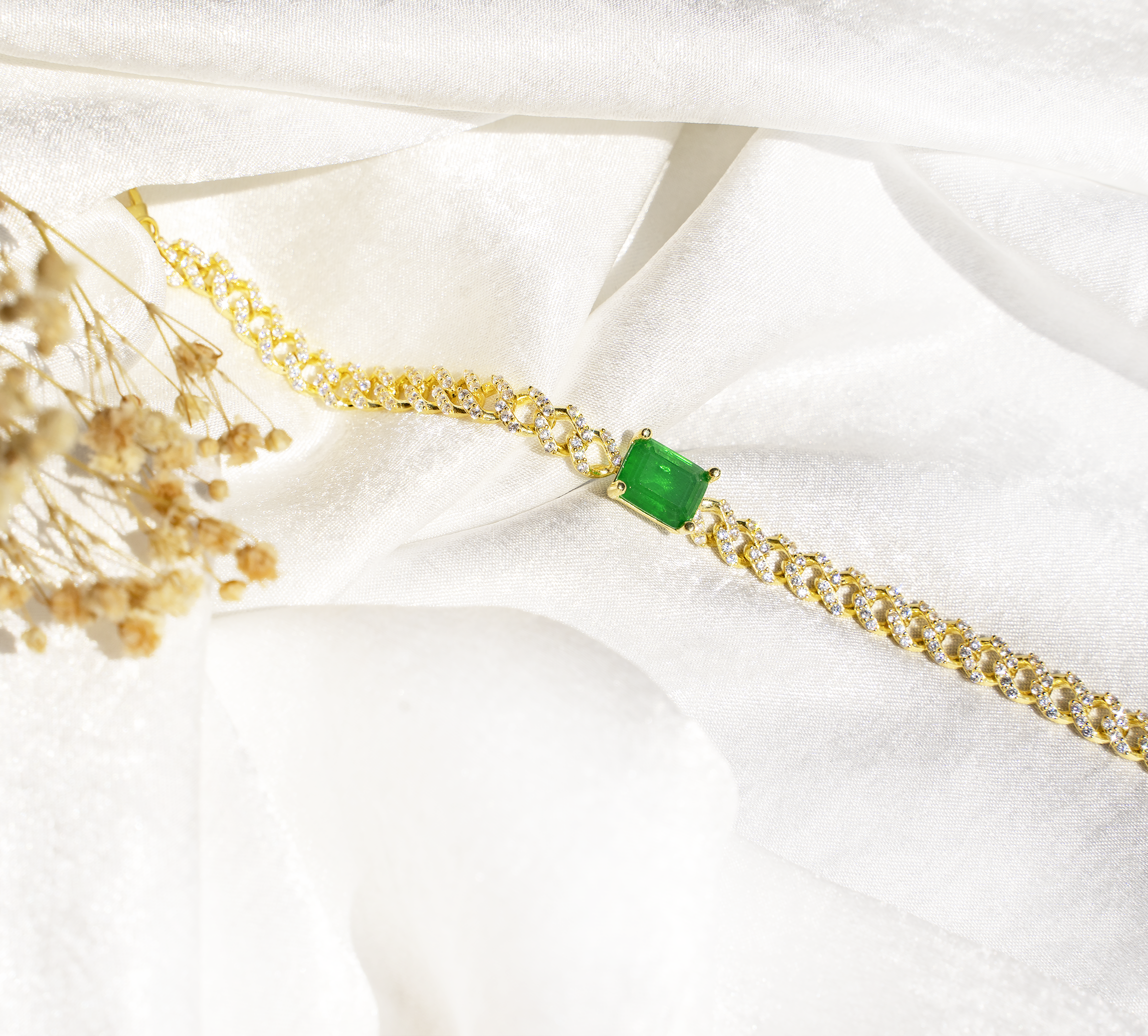 ALYA Bracelet featuring a chunky Miami curb chain with cubic zirconias and an emerald stone, elegantly designed in yellow gold plating.