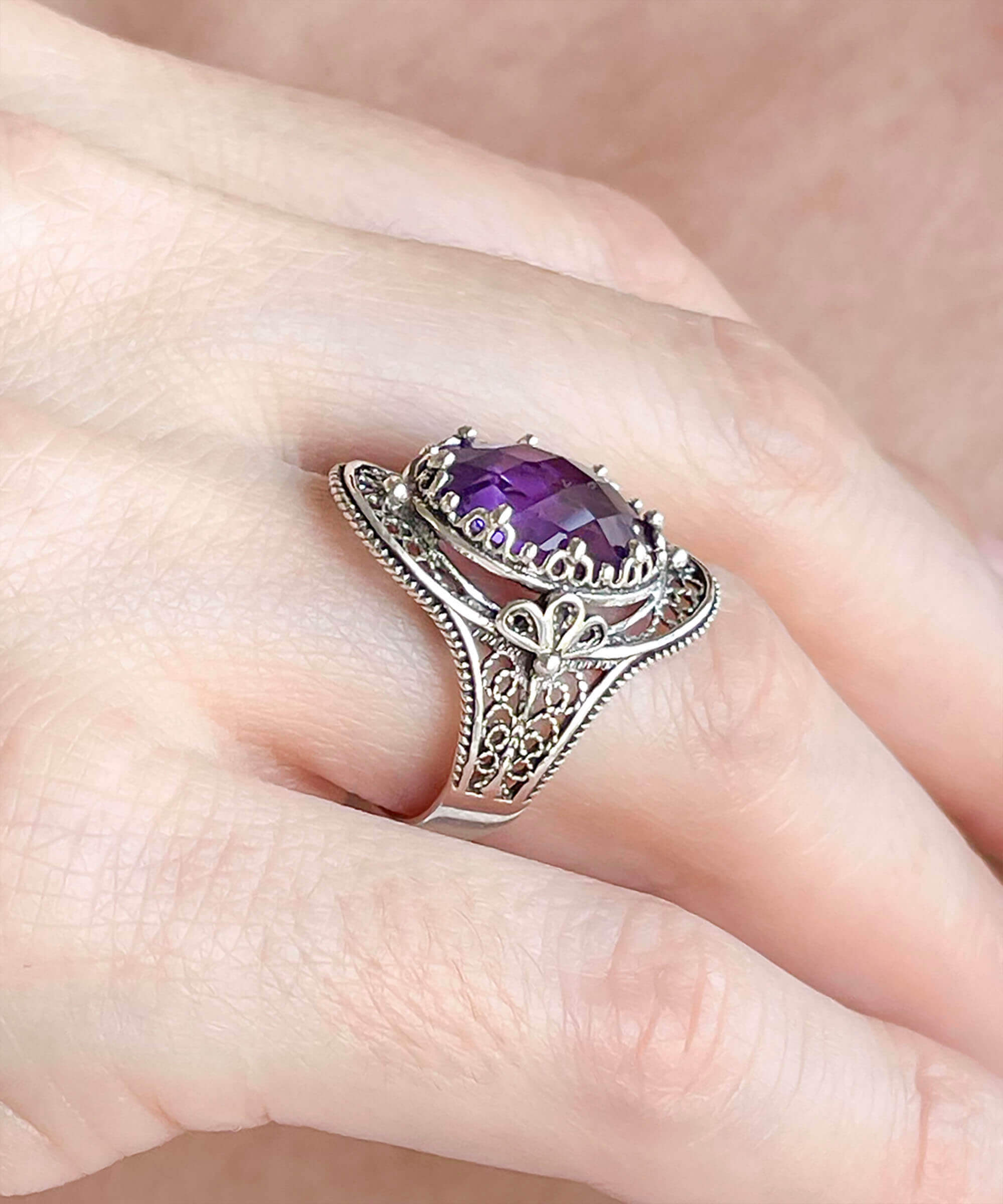 A stunning handmade silver statement ring featuring a double-sided oval cut amethyst gemstone in a delicate filigree design.