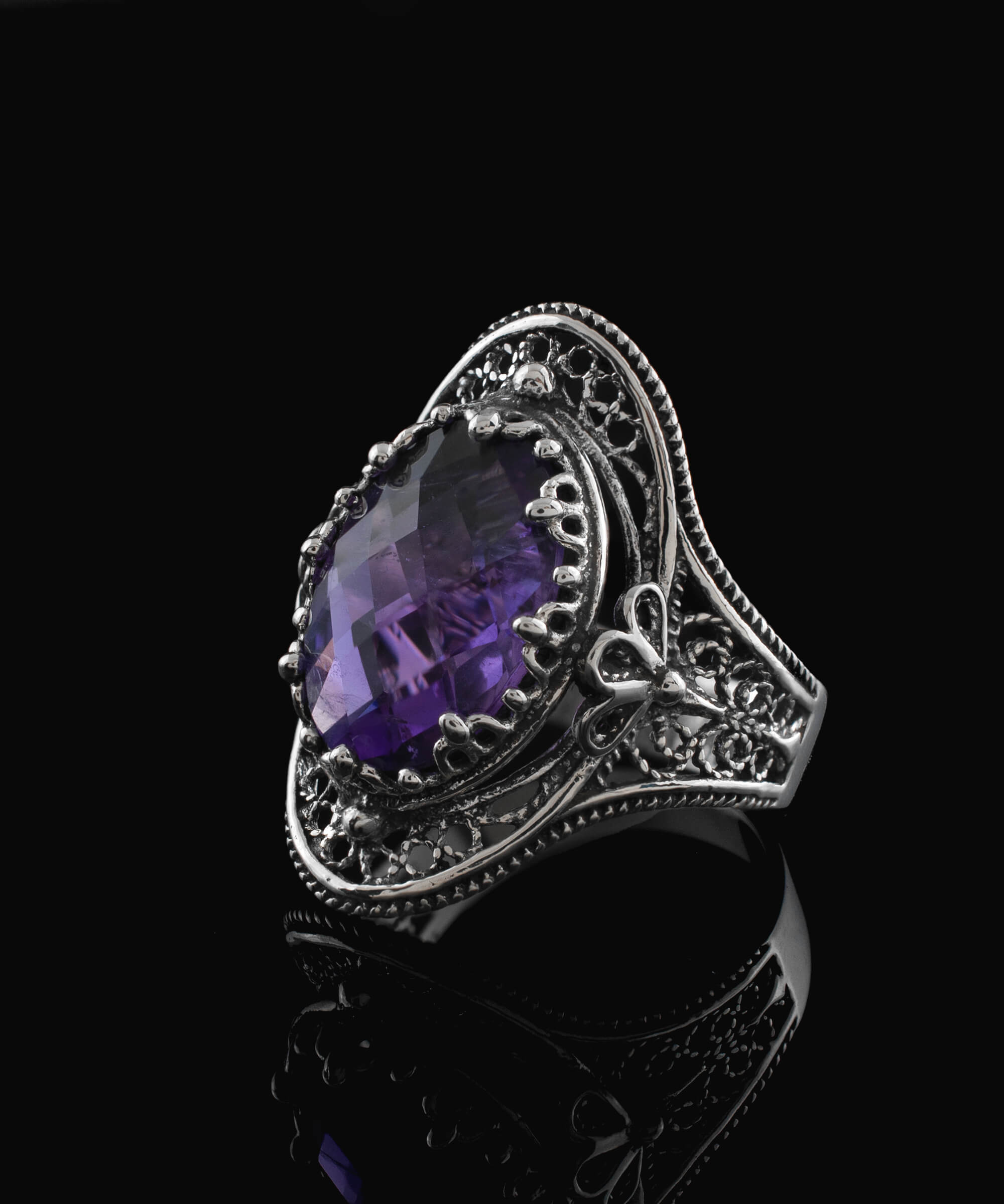 A stunning handmade silver statement ring featuring a double-sided oval cut amethyst gemstone in a delicate filigree design.